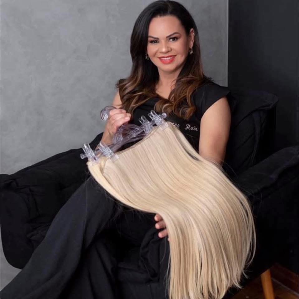 Profissional da Alê Hair apresentando peças de cabelo loiro